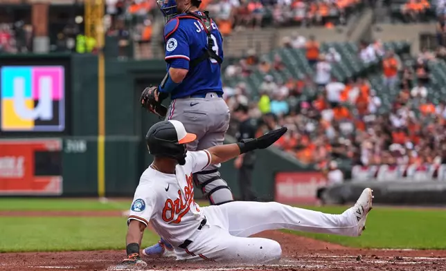 Baltimore Orioles' Leody Taveras scores past Texas Rangers catcher Danny Jansen on an RBI double hit by Taylor Ward during the second inning of a baseball game, Wednesday, April 1, 2026, in Baltimore. (AP Photo/Stephanie Scarbrough)