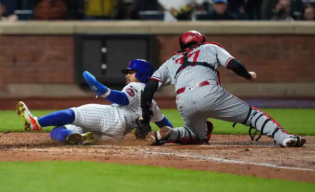 New York Mets' Francisco Lindor, left, slides past Minnesota Twins catcher Victor Caratini to score on a double by Francisco Alvarez during the fourth inning of a baseball game Wednesday, April 22, 2026, in New York. (AP Photo/Frank Franklin II)