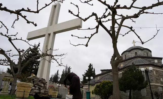 A monk tends to plants at the Monastery of St. Augustine and Seraphim of Sarov in the village of Trikorfo, about 236 kilometers (147 miles) northwest of Athens, Friday, March 20, 2026. (AP Photo/Thanassis Stavrakis)