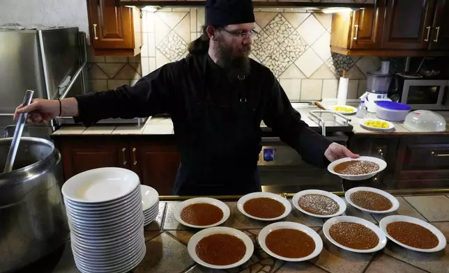 Father Isaac serves lentils for the midday meal at the Monastery of St. Augustine and Seraphim of Sarov in the village of Trikorfo, about 236 kilometers (147 miles) northwest of Athens, Friday, March 20, 2026. (AP Photo/Thanassis Stavrakis)