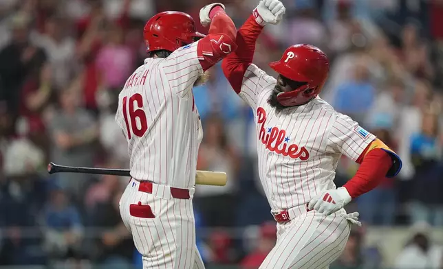 Philadelphia Phillies' Adolis García, right, celebrates his home run off of Washington Nationals pitcher Zack Littell with teammate Brandon Marsh during the fourth inning of a baseball game, Tuesday, March 31, 2026, in Philadelphia. (AP Photo/Matt Rourke)