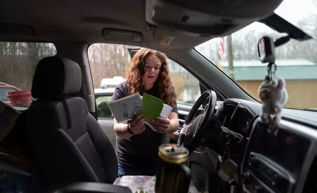 Ashley Nicole Dixon looks through her truck for electric bills outside one of her homes in Danese, W.Va., Saturday, March 21, 2026. (AP Photo/Carolyn Kaster)