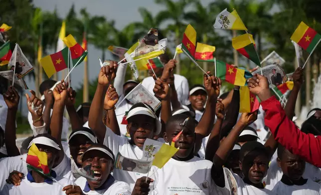 Children wave Cameroon and Vatican flags to greet Pope Leo XIV upon his arrival in Yaounde, Cameroon, Wednesday, April 15, 2026, on the third day of an 11-day apostolic journey to Africa. (AP Photo/Andrew Medichini)