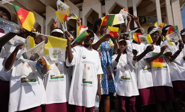 Children wave Cameroon and Vatican flags to greet Pope Leo XIV upon his arrival in Yaounde, Cameroon, Wednesday, April 15, 2026, on the third day of an 11-day apostolic journey to Africa. (AP Photo/Andrew Medichini)