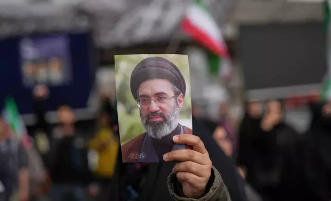 A demonstrator holds a picture of Iran's Supreme Leader Mojtaba Khamenei during a gathering after announcement of a two-week ceasefire with the United States and Israel, in Tehran, Iran, Wednesday, April 8, 2026. (AP Photo/Francisco Seco)