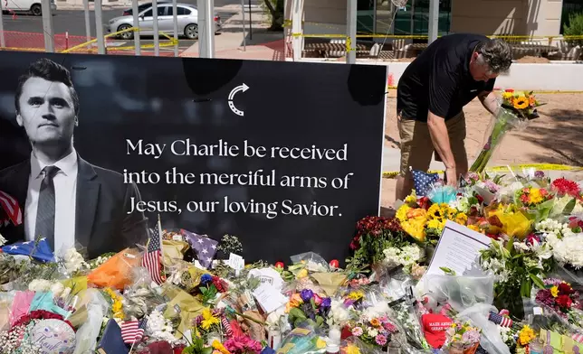 FILE - A well-wisher places flowers at a makeshift memorial set up for Charlie Kirk at Turning Point USA headquarters, Sept. 11, 2025, in Phoenix. (AP Photo/Ross D. Franklin, File)