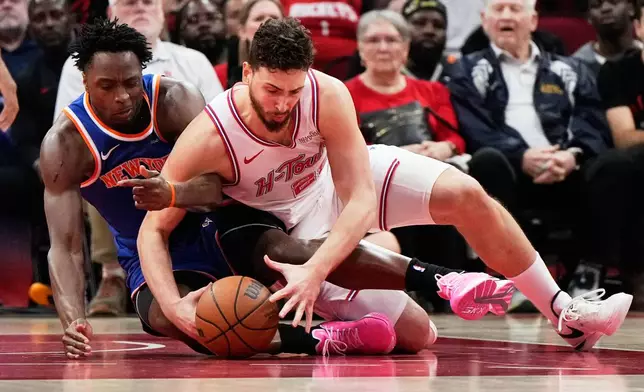New York Knicks forward Og Anunoby and Houston Rockets center Alperen Sengun (28) reach for a loose ball during the first half of an NBA basketball game in Houston, Tuesday, March 31, 2026. (AP Photo/Ashley Landis)
