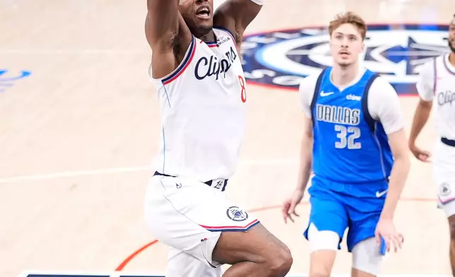 Los Angeles Clippers guard Kris Dunn, left, dunks as Dallas Mavericks forward Cooper Flagg watches during the first half of an NBA basketball game Tuesday, April 7, 2026, in Inglewood, Calif. (AP Photo/Mark J. Terrill)