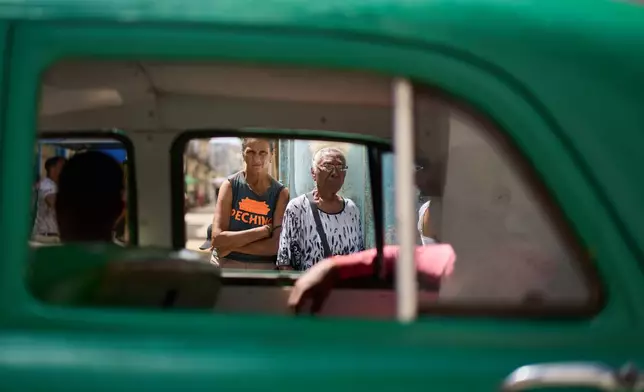 Seen through the window of a passing American classic car, seniors stand in line to buy bread in Old Havana, Cuba, Friday, April 10, 2026. (AP Photo/Ramon Espinosa)