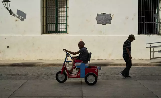 An elderly man who has an amputated leg rides a hand-powered tricycle in Old Havana. Cuba, Thursday, Feb. 20, 2025. (AP Photo/Ramon Espinosa)