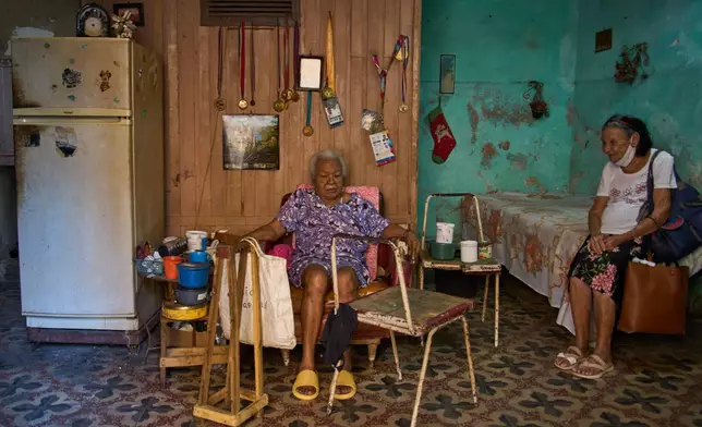 Mercedes Lopez Rey, 83, right, visits with her friend Julia Barcelo, 83, who is recovering from breast cancer treatment, after bringing her a meal from a church-sponsored program, in Old Havana. Cuba, Friday, April 10, 2026. (AP Photo/Ramon Espinosa)