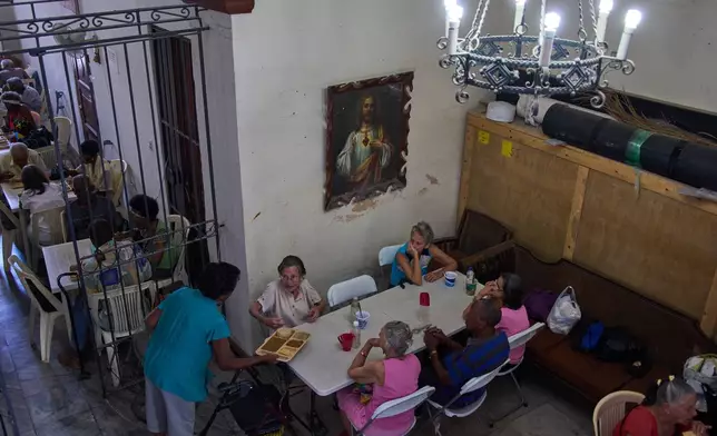 Carmen Casado, 84, is served a free meal of ground meat, rice, red beans and crackers through a program run by the Church of the Holy Spirit at a dining hall adjacent to the church in Old Havana, Cuba, Thursday, April 21, 2026. (AP Photo/Ramon Espinosa)