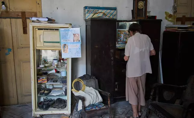 Carmen Casado, 84, looks through her wardrobe at her home in Old Havana, Cuba, Tuesday, April 21, 2026. (AP Photo/Ramon Espinosa)