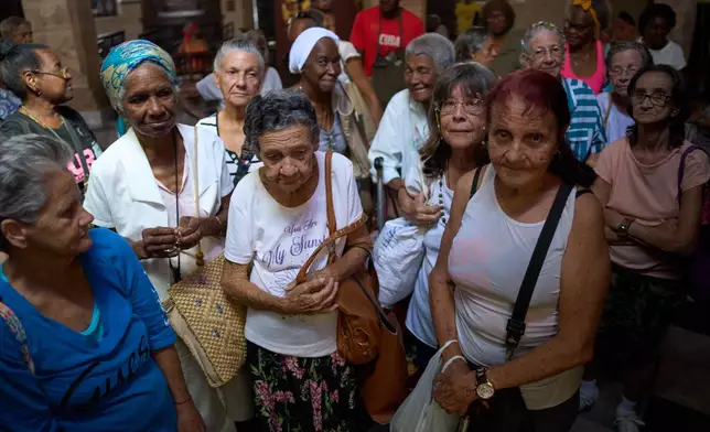 Mercedes Lopez Rey, 83, center front, and other elderly residents wait to be served a free meal in a dining hall adjacent to Church of the Holy Spirit where seniors gather three times a week for a free meal, in Old Havana, Cuba, Wednesday, April 15, 2026. (AP Photo/Ramon Espinosa)