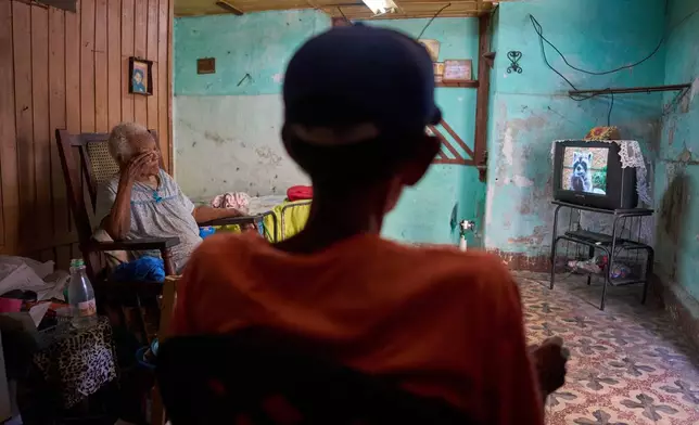 Julia Barcelo, 83, who is recovering from breast cancer treatment, and a visiting relative watch television at her home in Old Havana, Cuba, Friday, April 10, 2026. (AP Photo/Ramon Espinosa)