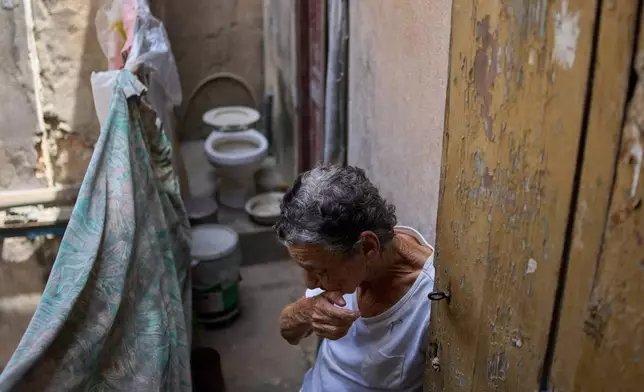 Mercedes Lopez Rey, 83, stands in her bathroom, holding open a patio door as a visitor leaves her one-room apartment in Old Havana, Friday, April 10, 2026. (AP Photo/Ramon Espinosa)