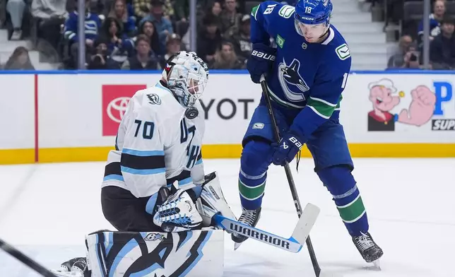 Utah Mammoth goalie Karel Vejmelka (70) makes the save as Vancouver Canucks' Drew O'Connor (18) stands in front of him during the third period of an NHL hockey game, in Vancouver, on Saturday, April 4, 2026. (Darryl Dyck/The Canadian Press via AP)