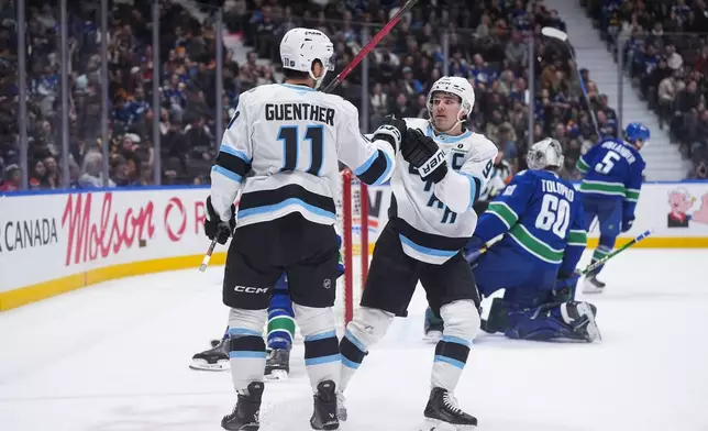 Utah Mammoth's Dylan Guenther (11) and Clayton Keller (9) celebrate Guenther's goal against Vancouver Canucks goalie Nikita Tolopilo (60) during the second period of an NHL hockey game, in Vancouver, on Saturday, April 4, 2026. (Darryl Dyck/The Canadian Press via AP)