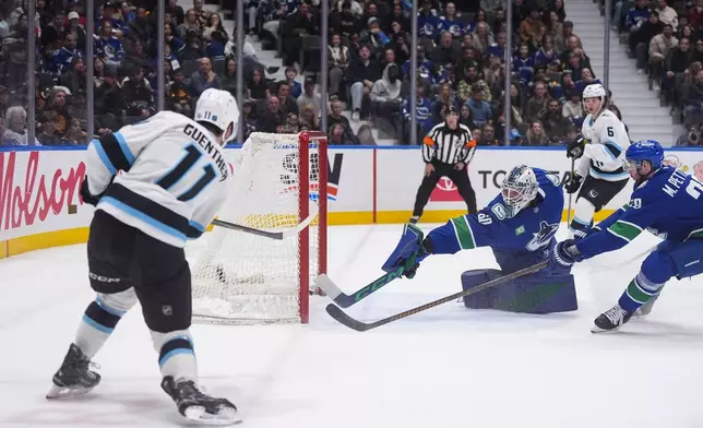 Utah Mammoth's Dylan Guenther (11) scores against Vancouver Canucks goalie Nikita Tolopilo (60) as Marcus Pettersson (29) defends during the second period of an NHL hockey game, in Vancouver, on Saturday, April 4, 2026. (Darryl Dyck/The Canadian Press via AP)