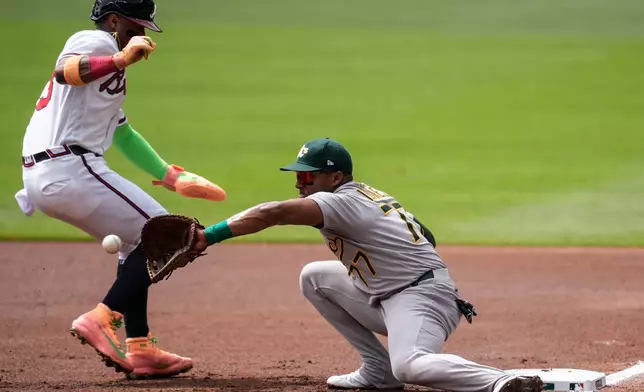 Athletics third baseman Andy Ibáñez (77) mags the tag on Atlanta Braves' Ronald Acuña Jr. (13) in the first inning of a baseball game, Wednesday, April 1, 2026, in Atlanta. (AP Photo/Mike Stewart)