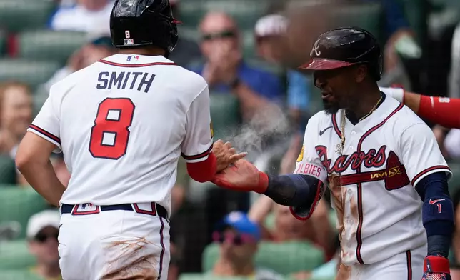 Atlanta Braves' Dominic Smith and Ozzie Albies, from left, celebrate scoring off the bat of Atlanta Braves' Drake Baldwin in the second inning of a baseball game against the Athletics, Wednesday, April 1, 2026, in Atlanta. (AP Photo/Mike Stewart)