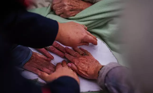 Participants and advisors put their hands on a cardboard box in the size of an elephant's foot during a guided tour for people with dementia organized by Malteser Deutschland, part of the international Catholic aid organization Malteser Order of Malta, at the Zoo in Berlin, Germany, Thursday, March 26, 2026. (AP Photo/Markus Schreiber)