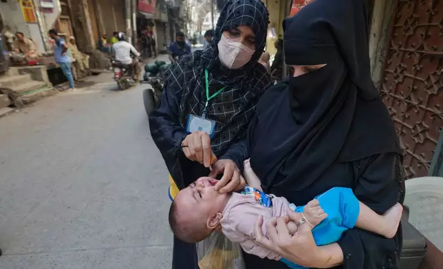 A health worker administers a polio vaccine to a child in Lahore, in Lahore, Pakistan, Monday, April 13, 2026. (AP Photo/K.M. Chaudary)