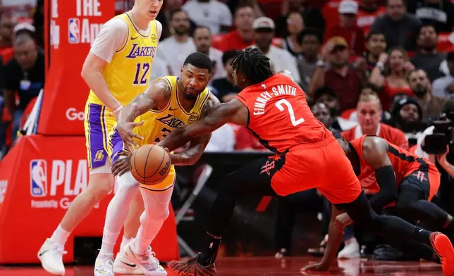 Houston Rockets forward Dorian Finney-Smith (2) knocks away the ball from Los Angeles Lakers guard Marcus Smart, center, as forward Jake LaRavia (12) looks on during the first half in Game 3 of a first-round NBA playoffs basketball series Friday April 24, 2026, in Houston. (AP Photo/Michael Wyke)