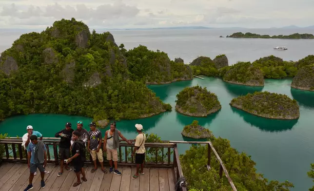 Tourists stand at a viewpoint overlooking the Waigeo Barat islands in Raja Ampat, Indonesia, Thursday, March 5, 2026. (AP Photo/Claudia Rosel)