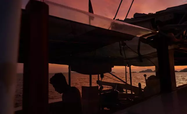 A crew member of the Raja Laut dive boat, is silhouette at sunrise aboard near Boo Windows diving site, Raja Ampat, Indonesia, Tuesday, March 3, 2026. (AP Photo/Claudia Rosel)
