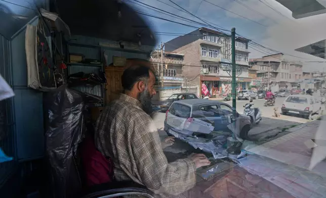 Irfan Ahmad checks census registration online at a registration center as the street is reflected on the glass in Srinagar, Indian controlled Kashmir, April 1, 2026. (AP Photo/Mukhtar Khan)