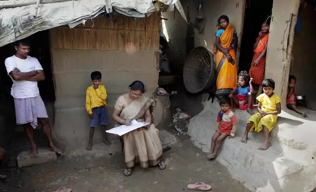 FILE -Mahesh Shah, left, stands as his family members look while census worker Rumima Das, writes the information on a paper on the first day of the national census at Ramsingh Chapori village, east of Gauhati, India, April 1, 2010. (AP Photo/Anupam Nath, File)