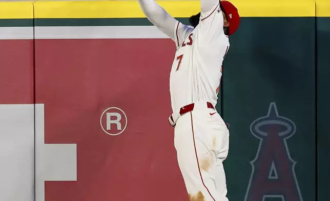 Los Angeles Angels left fielder Jo Adell (7) jumps up to catch a ball hit by Seattle Mariners' Josh Naylor (12) during the eighth inning of a baseball game Saturday, April 4, 2026, in Anaheim, Calif. (AP Photo/Caroline Brehman)