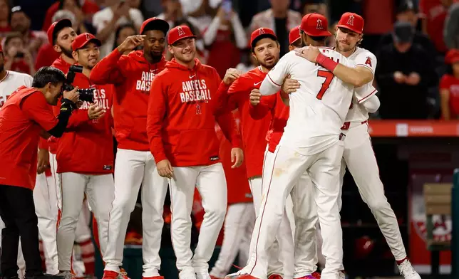 Los Angeles Angels Jo Adell (7) is greeted by teammates at the end of a baseball game against the Seattle Mariners, Saturday, April 4, 2026, in Anaheim, Calif. (AP Photo/Caroline Brehman)
