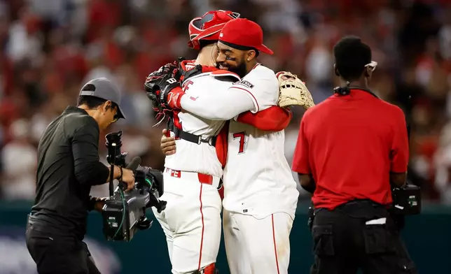 Los Angeles Angels catcher Logan O'Hoppe (14) and left fielder Jo Adell (7) embrace at the end of a baseball game against the Seattle Mariners, Saturday, April 4, 2026, in Anaheim, Calif. (AP Photo/Caroline Brehman)