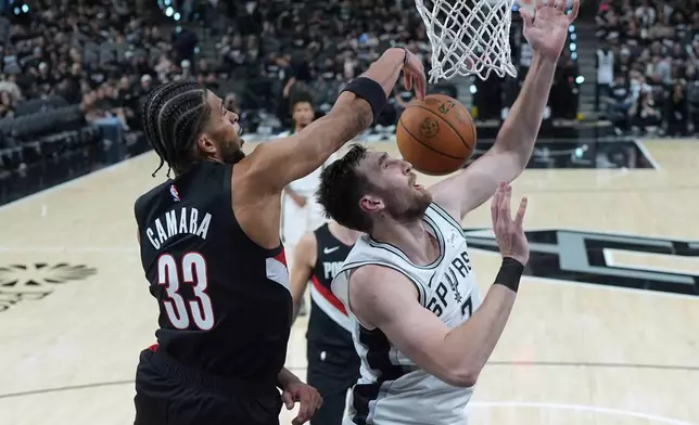 San Antonio Spurs center Luke Kornet (7) is blocked by Portland Trail Blazers forward Toumani Camara (33) during the second half in Game 2 of a first-round NBA playoffs basketball series in San Antonio, Tuesday, April 21, 2026. (AP Photo/Eric Gay)
