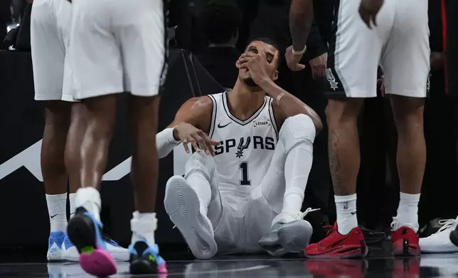 San Antonio Spurs forward Victor Wembanyama (1) sits on the court after a hard fall during the first half in Game 2 of a first-round NBA playoffs basketball series against the Portland Trail Blazers in San Antonio, Tuesday, April 21, 2026. (AP Photo/Eric Gay)