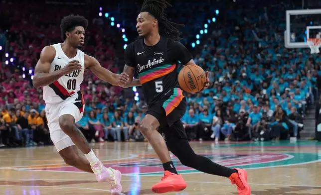 San Antonio Spurs guard Stephon Castle (5) drives against Portland Trail Blazers guard Scoot Henderson (00) during the second half in Game 1 of a first-round NBA playoffs basketball series in San Antonio, Sunday, April 19, 2026. (AP Photo/Eric Gay)