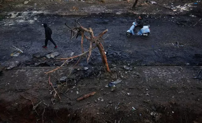 A man rides a scooter past a burned tree and charred debris following an Israeli strike in Beirut, Lebanon, Wednesday, April 1, 2026. (AP Photo/Hassan Ammar)
