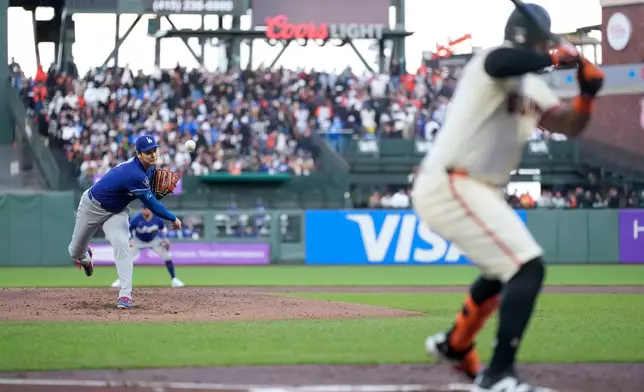 Los Angeles Dodgers pitcher Shohei Ohtani, left, throws to a San Francisco Giants' Heliot Ramos, right, during the second inning of a baseball game Wednesday, April 22, 2026, in San Francisco. (AP Photo/Tony Avelar)