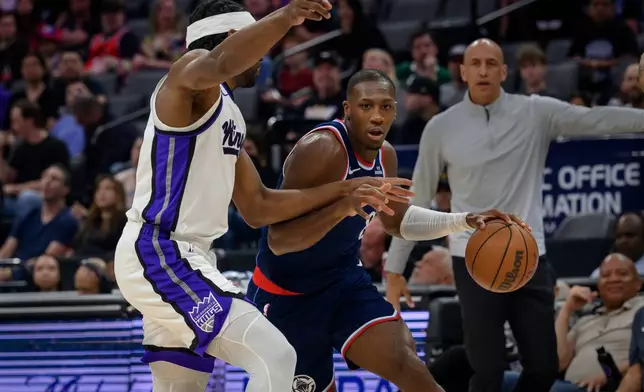 Los Angeles Clippers guard Kris, center, Dunn is guarded by Sacramento Kings forward Precious Achiuwa during the first half of an NBA basketball game in Sacramento, Calif., Sunday, April 5, 2026. (AP Photo/Randall Benton)