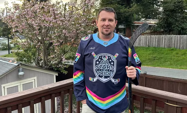 Steven Thompson, co-founder of the Seattle Pride Hockey Association (SPHA), poses for a photo with his stick that features pride tape and a SPHA sweater at his home in Des Moines, Wash., Monday, April 27, 2026. (AP Photo/Andrew Destin)
