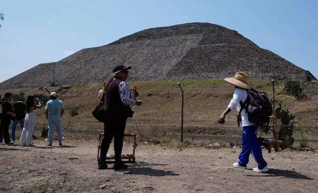 Handicraft vendors and tourists stand outside the Teotihuacan pyramids, which remained closed a day after a gunman opened fire on tourists at the archaeological site on the outskirts of Mexico City, Tuesday, April 21, 2026. (AP Photo/Marco Ugarte)