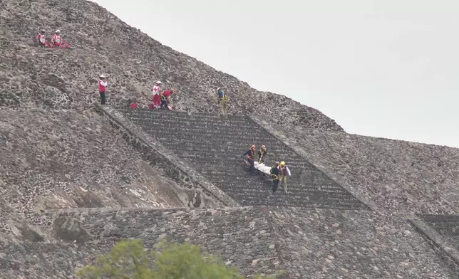 Forensic experts carry the body of a victim down a pyramid after authorities said a gunman opened fire in Teotihuacan, Mexico, Monday, April 20, 2026. (AP Photo/Eduardo Verdugo)