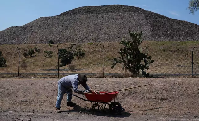 A worker pushes a wheelbarrow at the Teotihuacan pyramids, which remained closed a day after a gunman opened fire on tourists at the archaeological site on the outskirts of Mexico City, Tuesday, April 21, 2026. (AP Photo/Marco Ugarte)