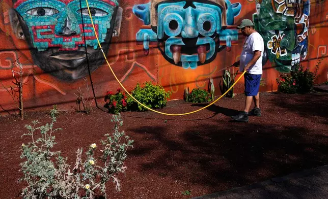 A man waters plants outside a handicrafts shop near the Teotihuacan pyramids, which remained closed a day after a gunman opened fire on tourists at the archaeological site outside Mexico City, Tuesday, April 21, 2026. (AP Photo/Marco Ugarte)