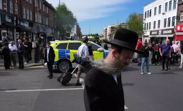 A man walks past a blocked road after two people were stabbed in Golders Green neighbourhood, that has a large Jewish community, in London, Wednesday, April 29, 2026.(AP Photo/Kin Cheung)