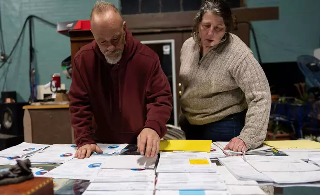 Lock 24 RV Park and Campground manager Eric Pinson, left, and Kirsten Haas pore over the campground's electric bills, at their home at the campground in Racine, Ohio, Friday, March 13, 2026. (AP Photo/Carolyn Kaster)