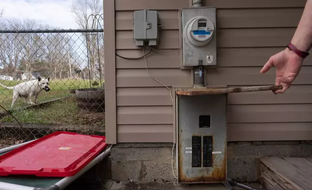 Ashley Nicole Dixon shows her electrical panel below the electric meter as one of her rescued dogs, Lola, holds a toy, at her home in Danese, W.Va., Saturday, March 21, 2026. (AP Photo/Carolyn Kaster)