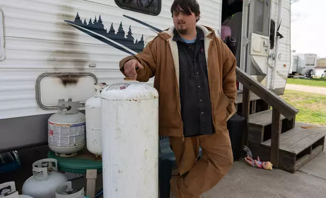 John White Jr., stands near propane tanks he uses for cooking outside his home at the Lock 24 RV Park and Campground in Racine, Ohio, Saturday, March 14, 2026, across the Ohio River from the coal-fired Mountaineer Power Plant, near New Haven, W.Va. (AP Photo/Carolyn Kaster)
